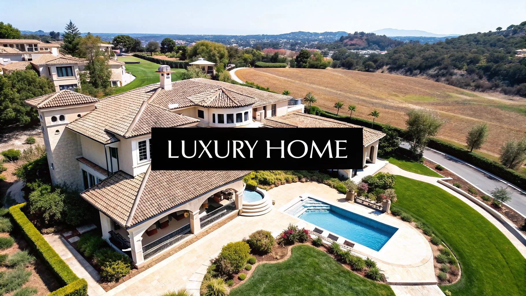 Aerial view of a sprawling luxury home with a swimming pool, green lawn, and scenic hills.